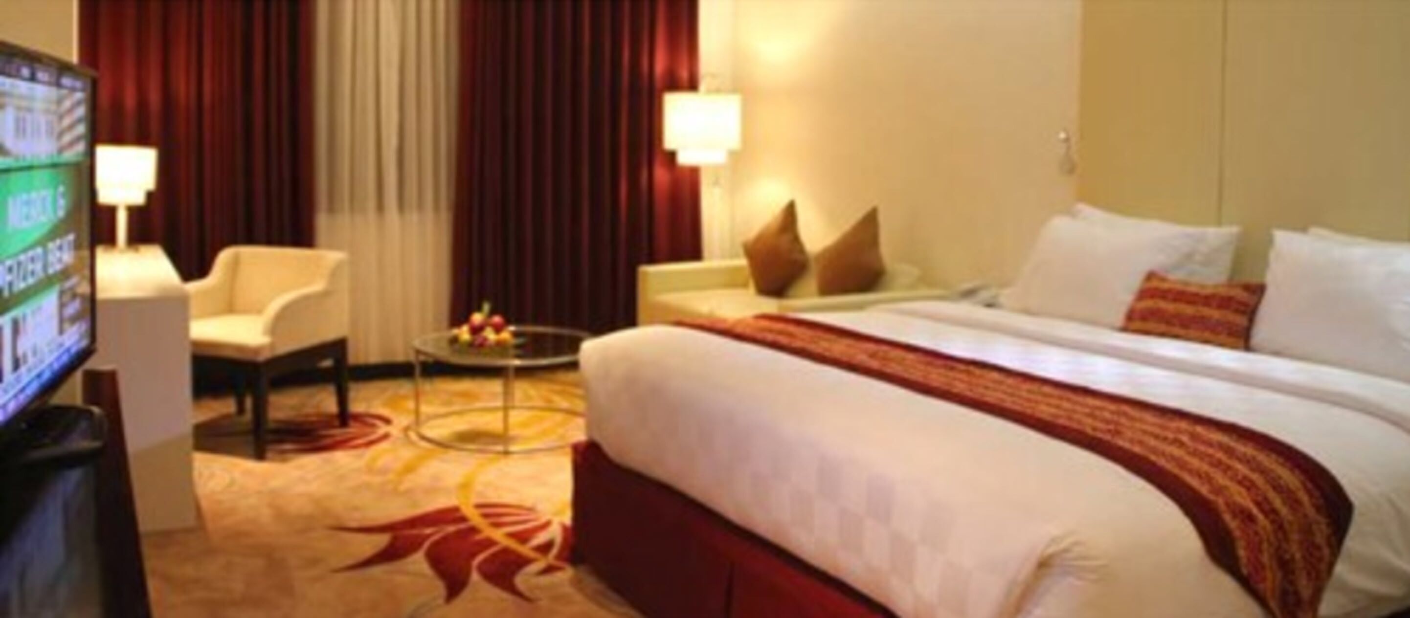 A hotel room with a bed, a TV, a desk, and a chair.