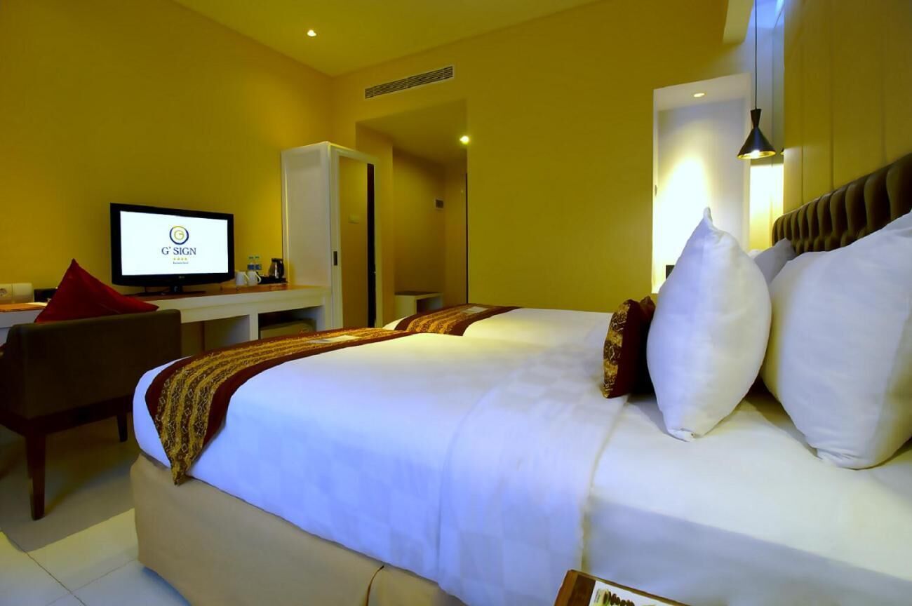 A hotel room with a bed, a desk, a television, and a wardrobe.