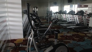Une salle de sport équipée de vélos d’appartement, de tapis de course et d’autres appareils d’exercice.