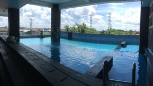 Une piscine à l’eau d’un bleu cristallin, entourée d’une terrasse carrelée et d’un petit muret.
