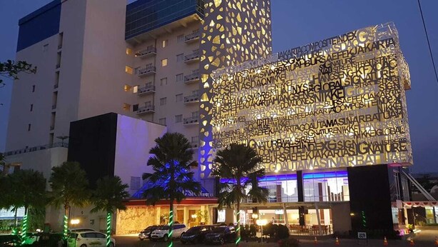 Un hôtel moderne à la façade originale, caractérisée par un motif de panneaux réfléchissants et un logo bien visible sur le dessus.