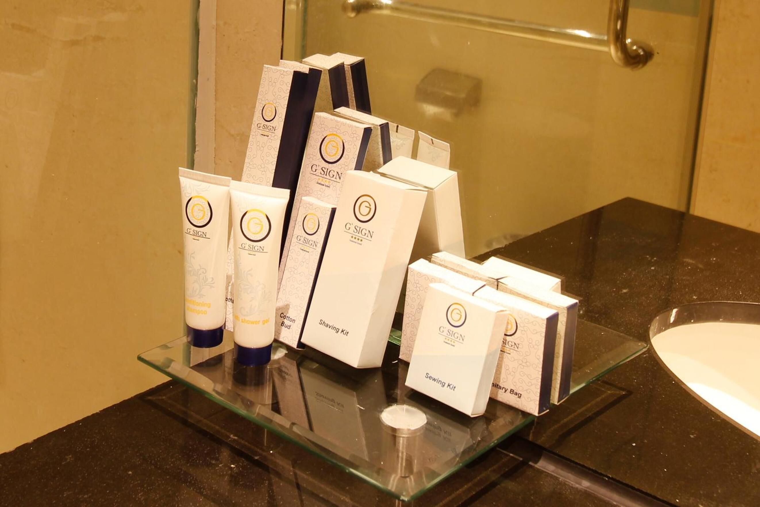 A bathroom counter with various G'Sign personal care products, including shaving kits and sewing kits.