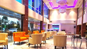 Un hall d’entrée spacieux, doté d’un mobilier moderne, d’un grand lustre et offrant une vue sur l’extérieur grâce à de larges fenêtres.