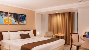 Habitación de hotel con una cama grande, una mesita redonda pequeña, una silla y un cuadro en la pared.