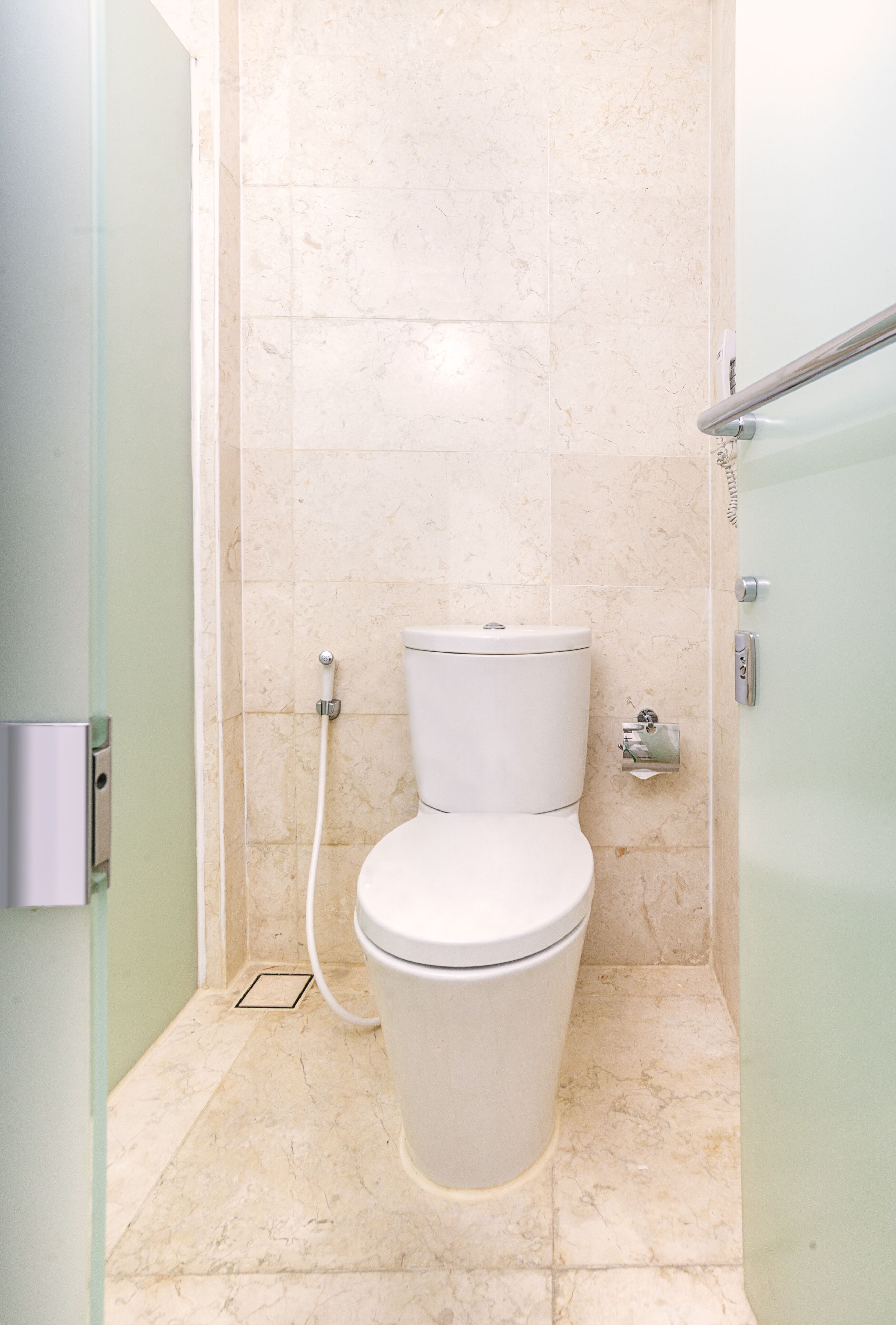 A modern bathroom with a toilet, a shower area, and a glass door.