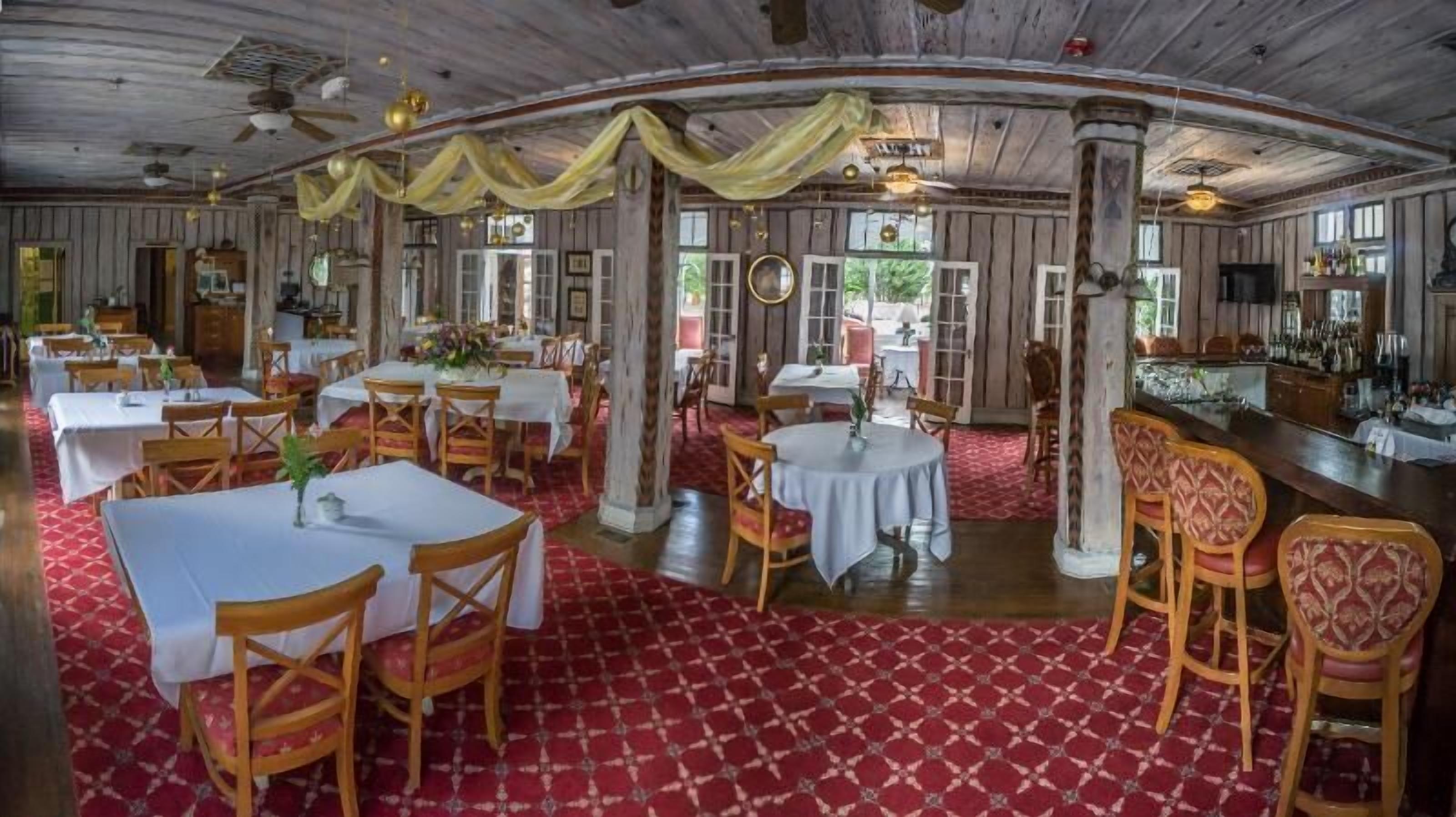A restaurant with wooden walls, white tables, and red patterned flooring.