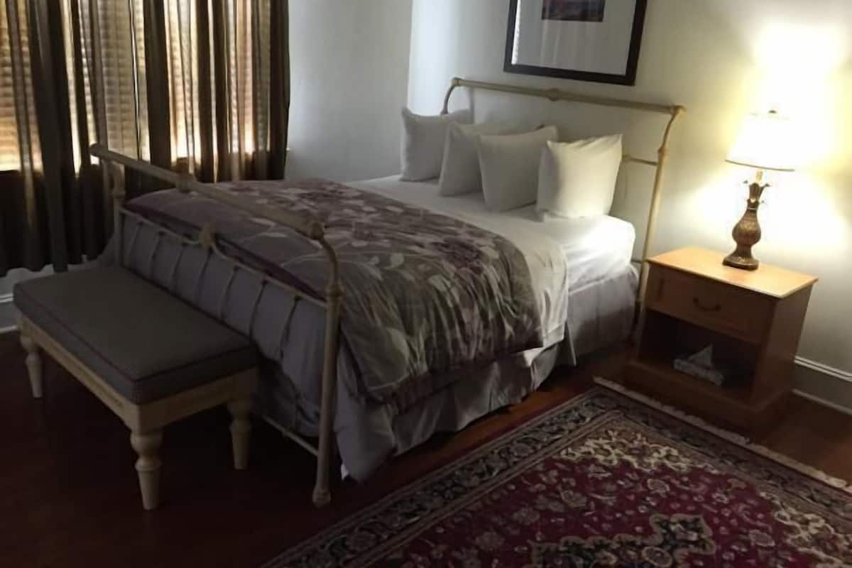 Une chambre à coucher avec un lit, une table de chevet, une lampe et un banc.