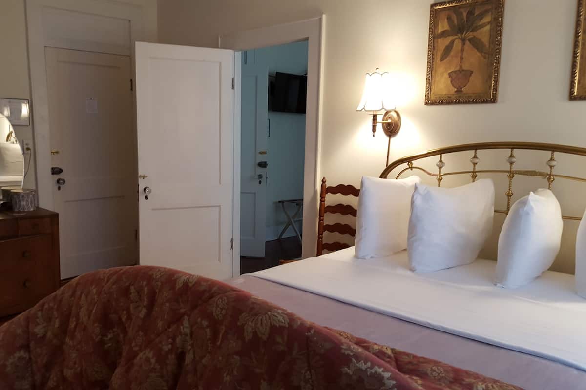 Une chambre d’hôtel comprenant un lit, une commode, un miroir, une télévision et une lampe.
