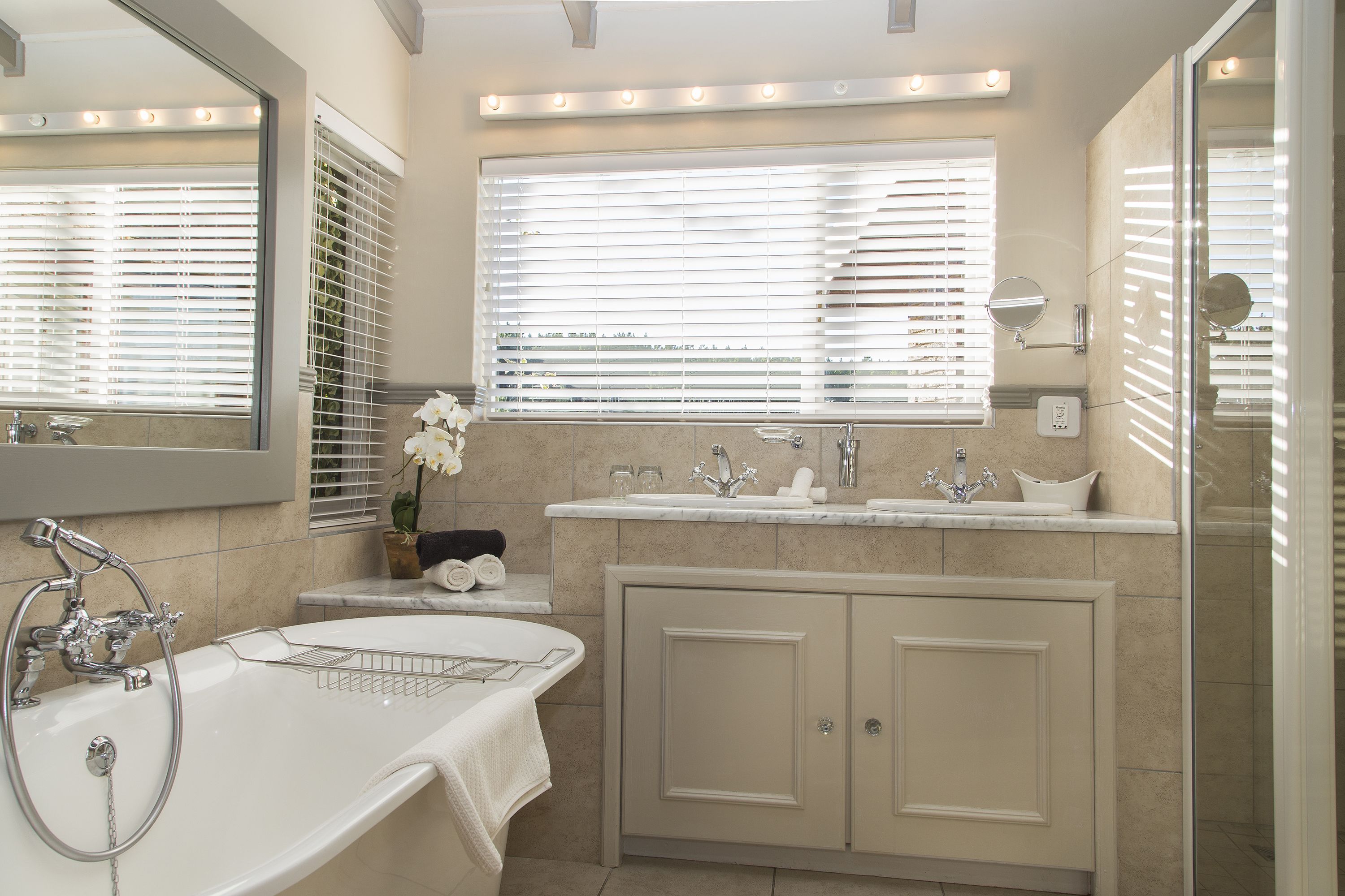Un baño moderno con una bañera grande, un lavabo y un espejo sobre él.