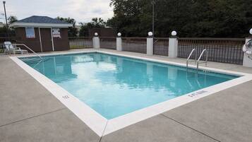 Una piscina rectangular con una escalera metálica y una cerca con remates esféricos.