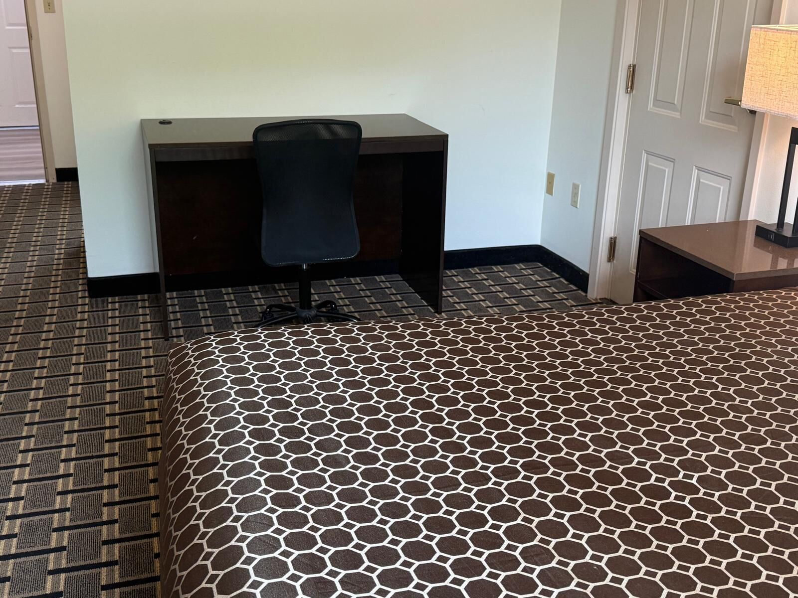 A hotel room with a bed, a desk, and a chair.
