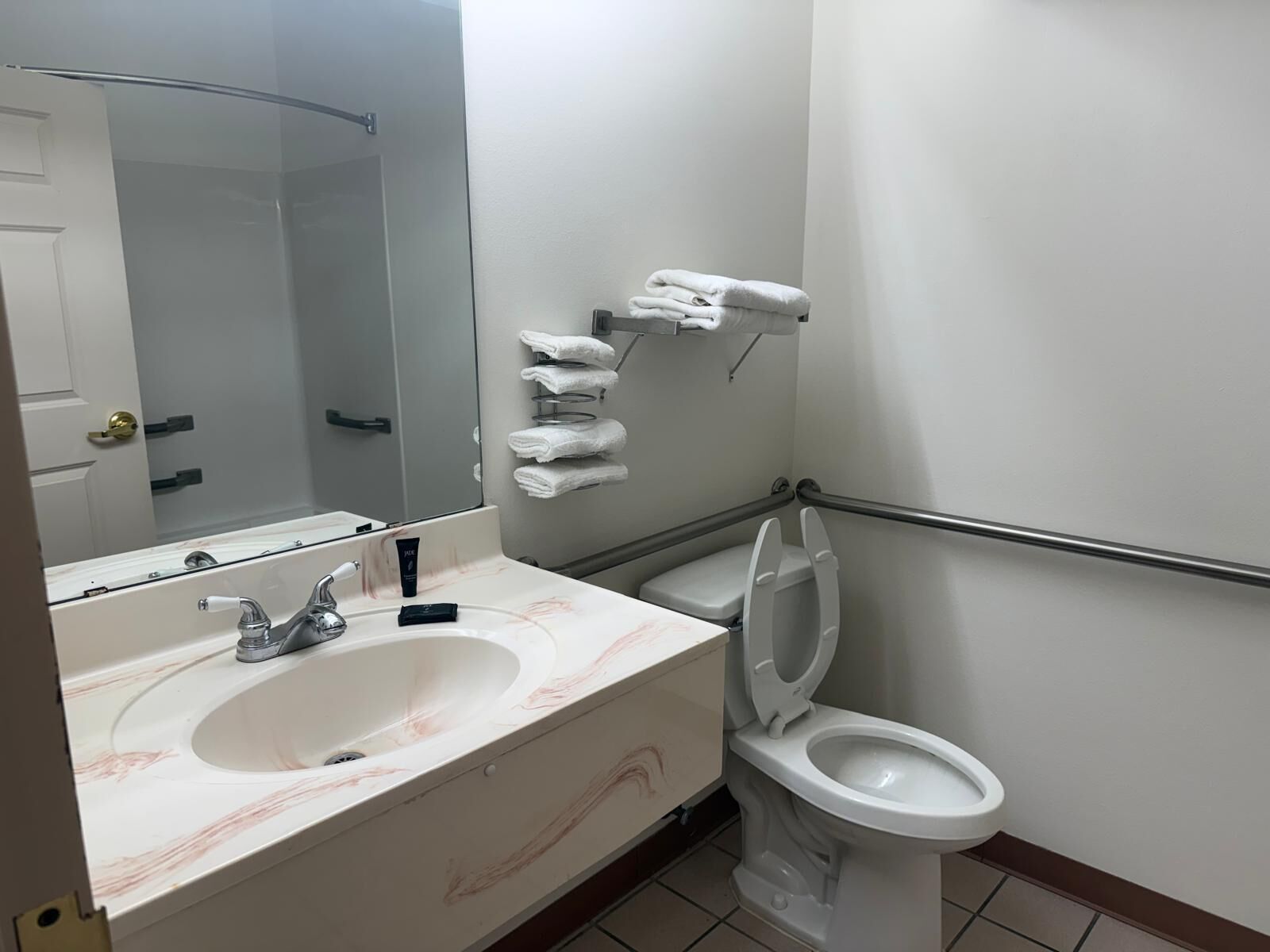 Une salle de bain équipée d’un lavabo, d’un miroir, de toilettes et d’un porte-serviettes.