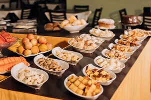 A buffet table with various food items including fruits, pastries, and desserts.