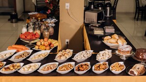 A buffet table with various food items and a coffee maker in the background. - Trindade Plaza Hotel (Trindade)