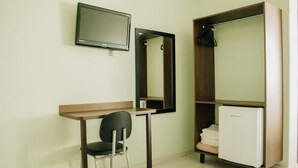 A small room with a desk, chair, mirror, wardrobe, and a television. - Trindade Plaza Hotel (Trindade)