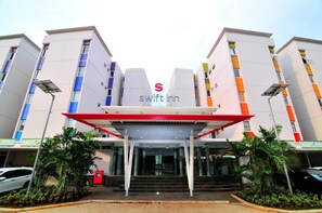 A modern hotel entrance with a red canopy and a 'Swift Inn' sign. - Swift Inn Aeropolis Airport (Tangerang)