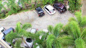 Vue aérienne d’un parking où se trouvent plusieurs voitures et de grands arbres aux feuillages luxuriants.
