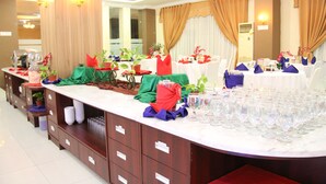 Une salle de banquet avec des tables rondes dressées pour un événement formel, agrémentée de verres et d’une décoration de table élégante.