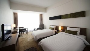 A hotel room with two beds, a desk with a laptop, a TV, and a chair. - Premiere by Grand Zuri (Pekanbaru)