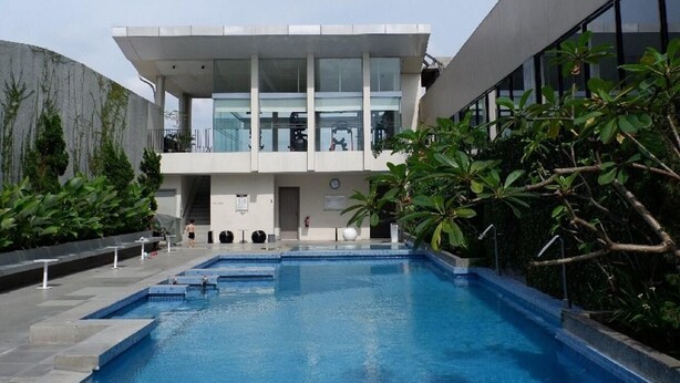 A modern building with a swimming pool in front. - Premiere by Grand Zuri (Pekanbaru)