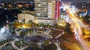 A multi-story hotel with a modern design, featuring a central courtyard with circular light arrangements. - Premiere by Grand Zuri (Pekanbaru)