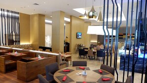 A modern hotel lobby with round tables, a reception area, and a view of the pool. - Premiere by Grand Zuri (Pekanbaru)