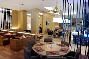 Un vestíbul d'hotel modern amb taules rodones, una zona de recepció i vista a la piscina.