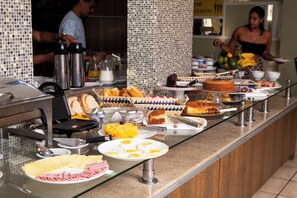 A buffet with various food items and a person serving. - Victoria Plaza Hotel (Palmas)