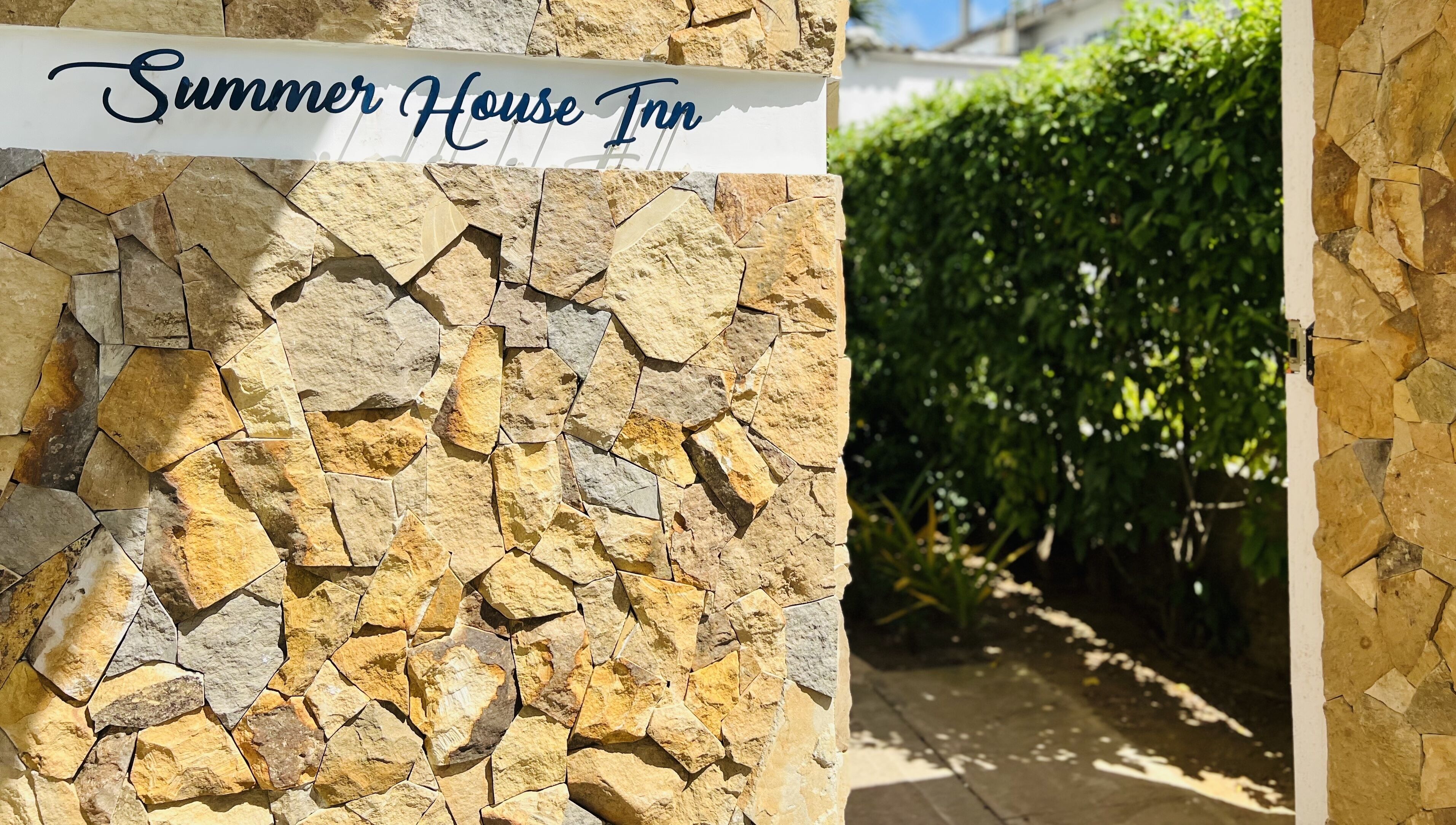 A stone wall with a sign reading "Summer House Inn".
