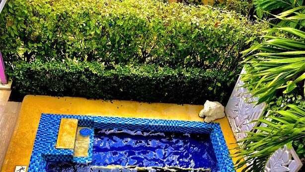 A small, square-shaped pool with a blue mosaic border and a central water feature. - Summer House Inn San Andres (San Andrés)