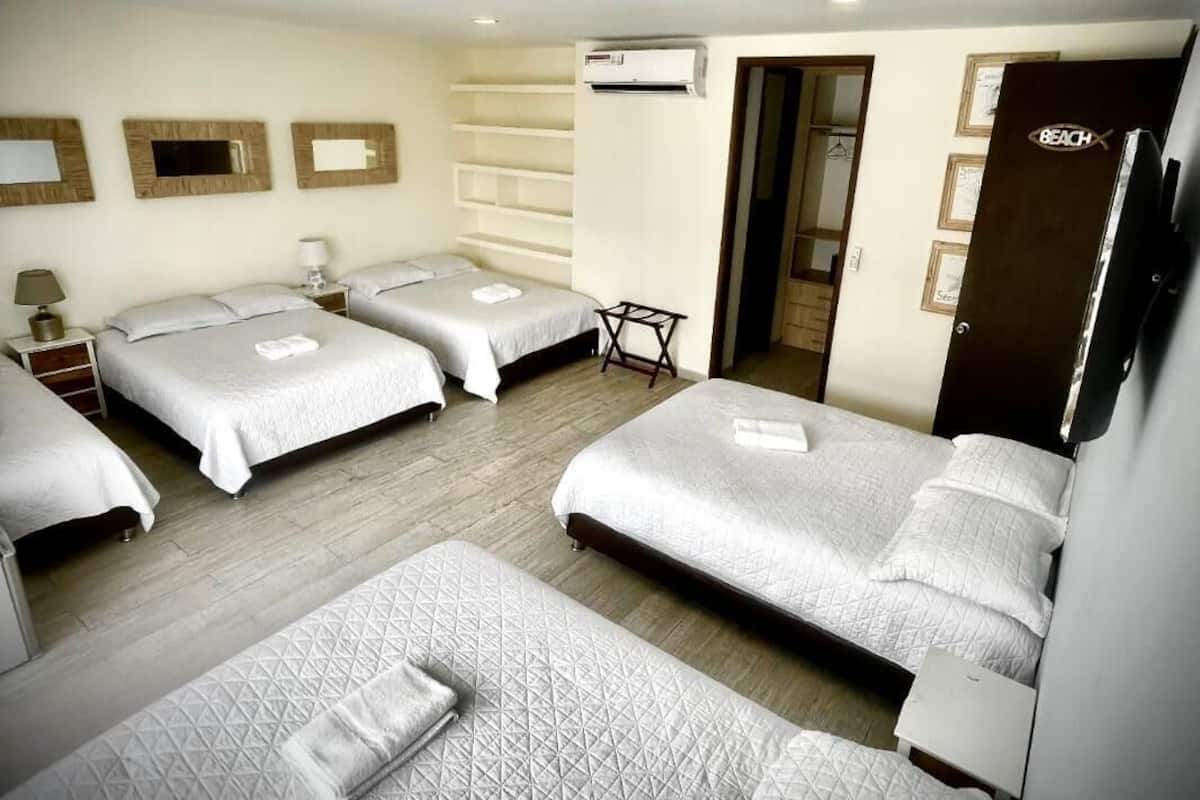 Una habitación de hotel con cuatro camas, una mesita, un armario y un equipo de aire acondicionado.