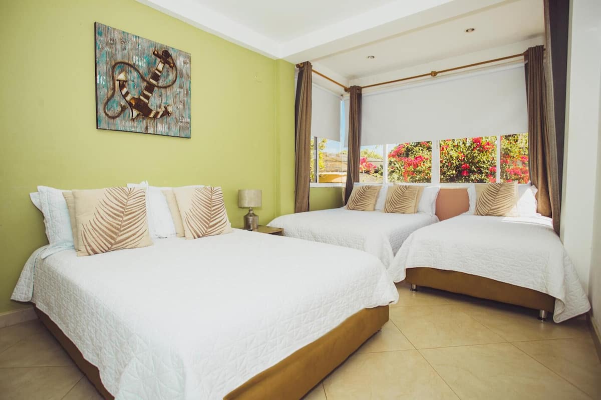 Habitación de hotel con dos camas, un cuadro en la pared y ventana con vistas a flores.