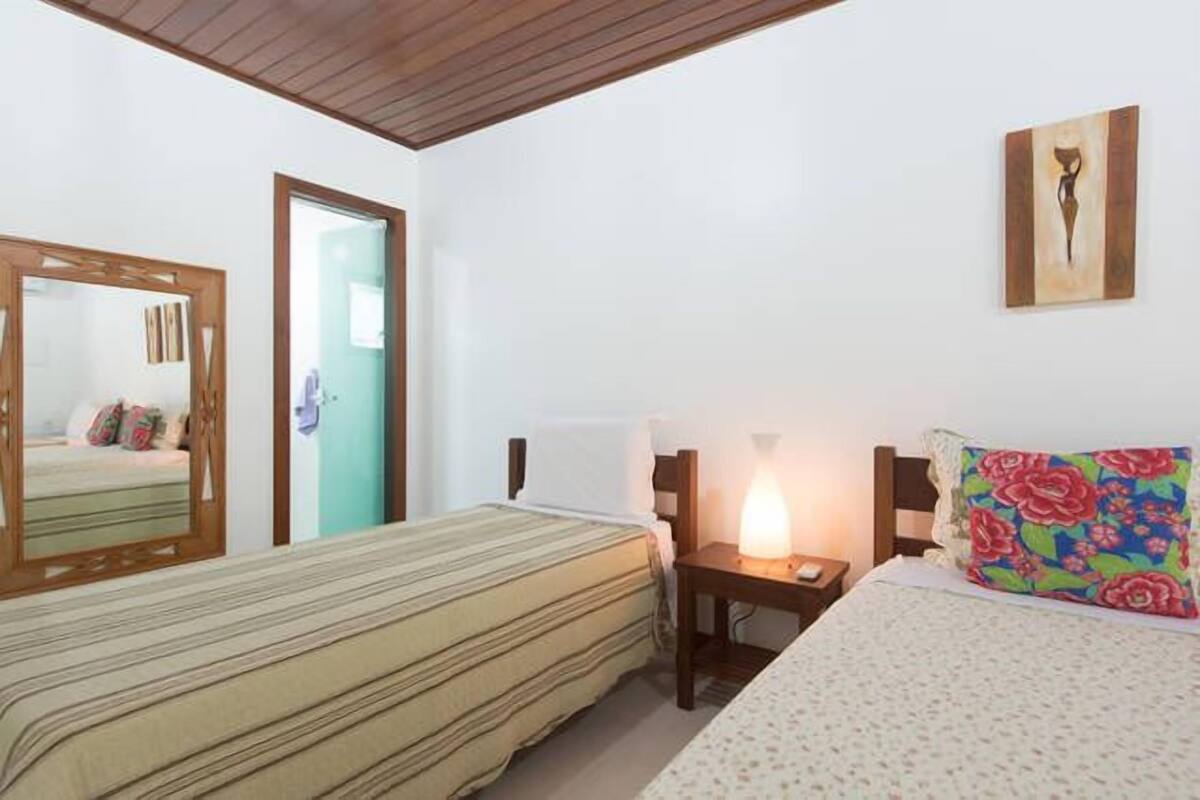 A bedroom with two beds, a nightstand, a mirror, and a painting on the wall.