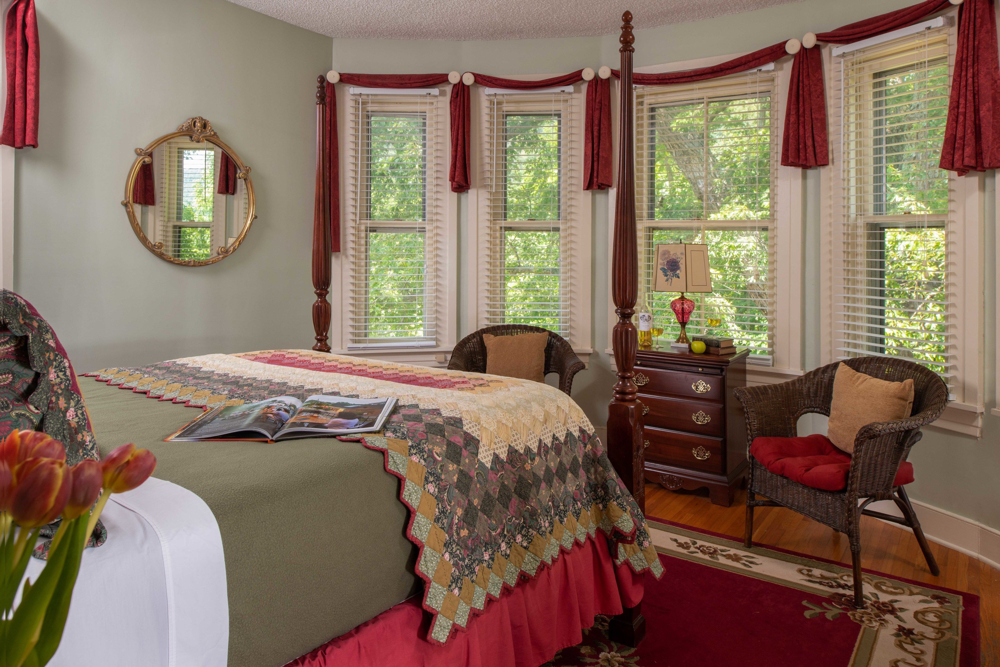 A bedroom with a large bed, a dresser, a chair, and a window with curtains.