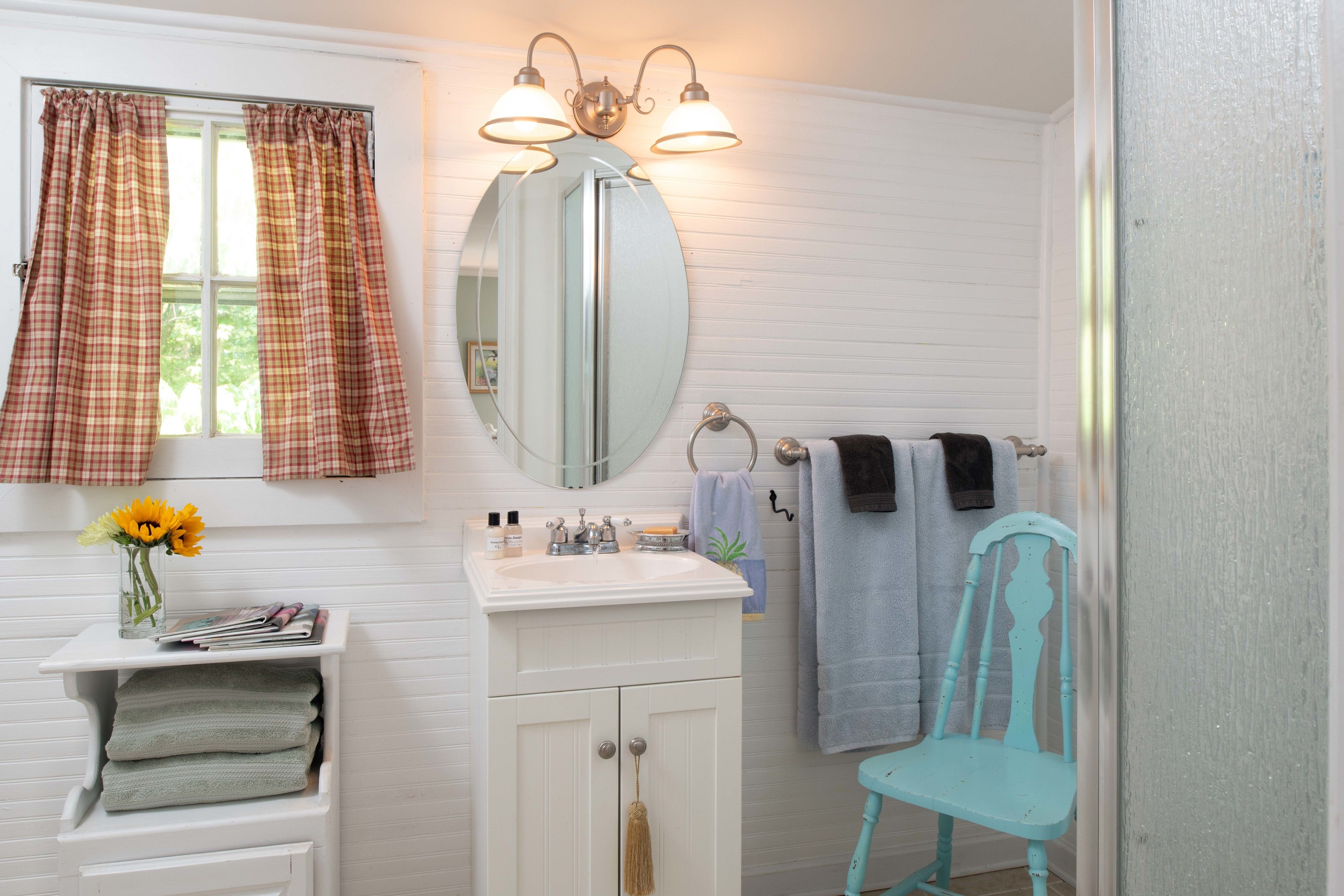 A bathroom with a white vanity, a mirror, a sink, and a chair.