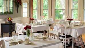 A dining area with multiple tables set for service, white chairs, and a sign indicating the restaurant's name. - Orchard House B&B (Lovingston)