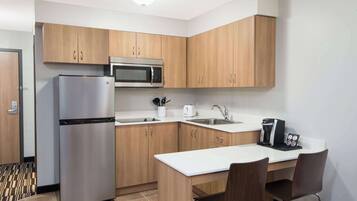 Cocina moderna con armarios de madera, un refrigerador de acero inoxidable, un microondas, un lavabo y una cafetera.