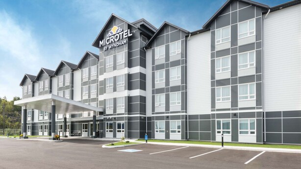 A modern Microtel by Wyndham hotel with a covered entrance, multiple floors, and a parking lot. - Microtel Inn & Suites by Wyndham Sudbury (Sudbury)