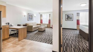 A hotel room with a kitchenette, a sofa, a bed, and a patterned carpet. - Microtel Inn & Suites by Wyndham Sudbury (Sudbury)