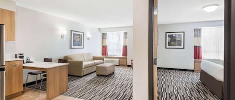 Una habitación de hotel con kitchenette, un sofá, una cama y una alfombra estampada.