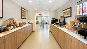 A modern kitchen area with wooden cabinets, a coffee station, and a seating area in the background. - Microtel Inn & Suites by Wyndham Sudbury (Sudbury)