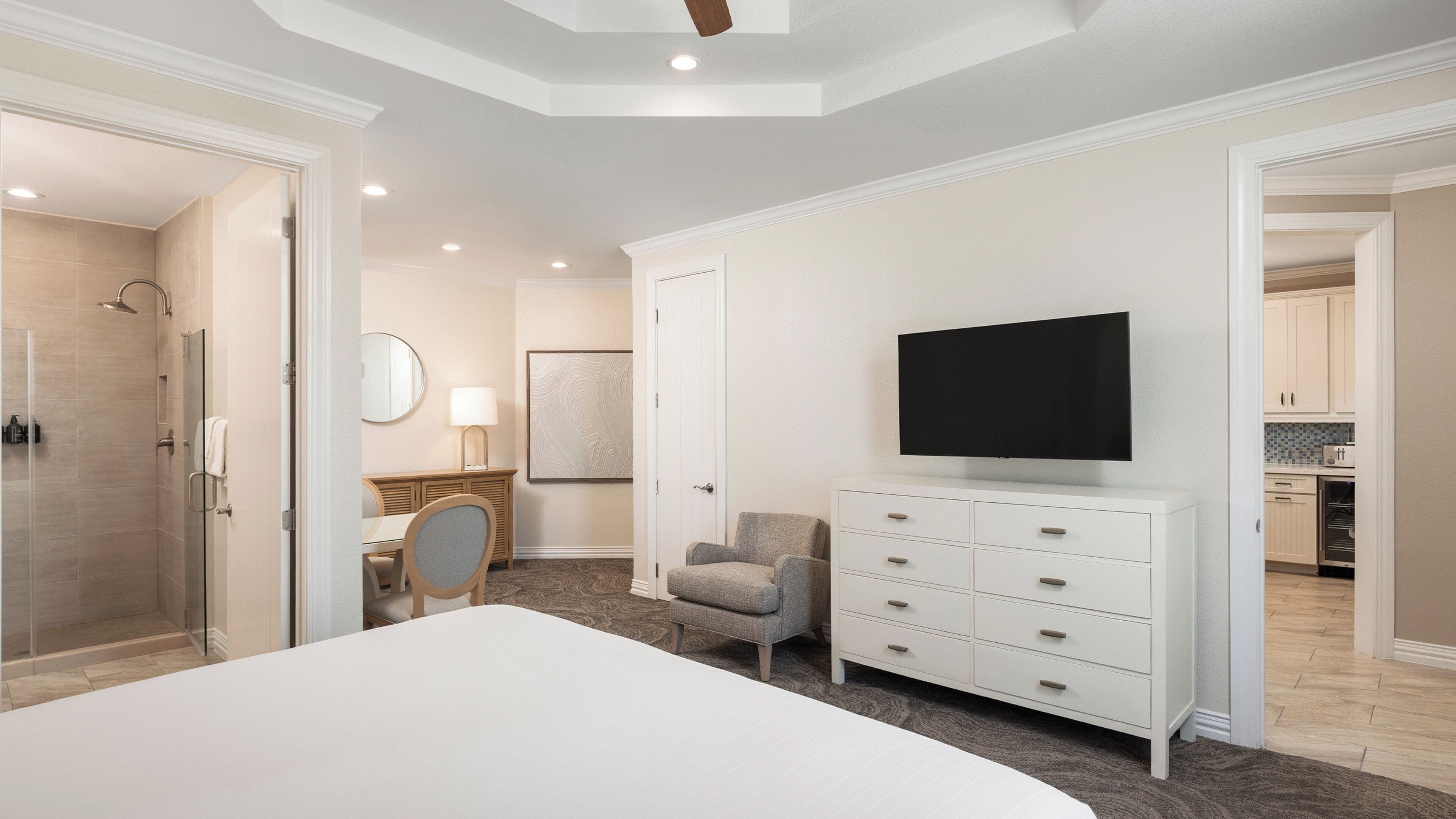 A modern bedroom with a large bed, a TV, a chair, and a desk.