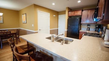 A kitchen with a large island, stainless steel appliances, wooden cabinets, and a dining area with chairs.