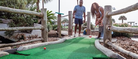 A miniature golf course with wooden obstacles and a green playing surface.