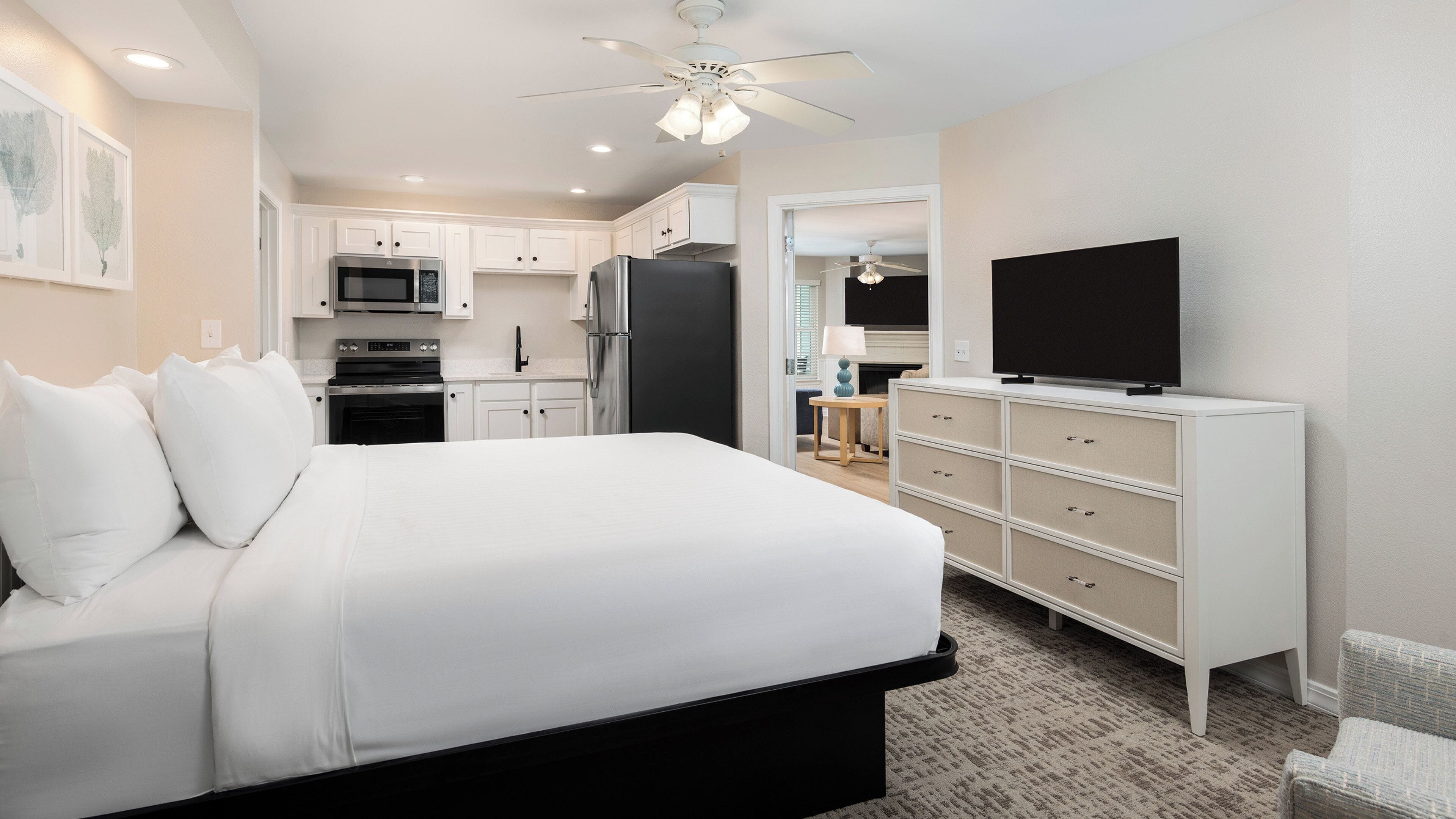 A hotel room with a bed, a TV, a dresser, a microwave, and a refrigerator.