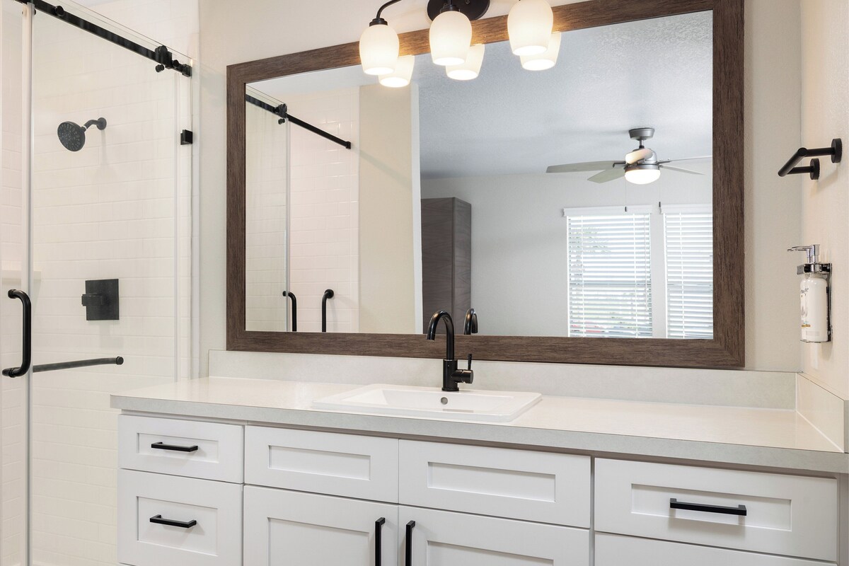 Une salle de bain moderne avec un meuble-lavabo blanc, un robinet noir et un grand miroir.