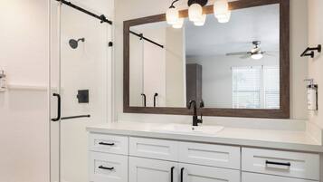 Un baño moderno con tocador blanco, grifo negro y un espejo grande.
