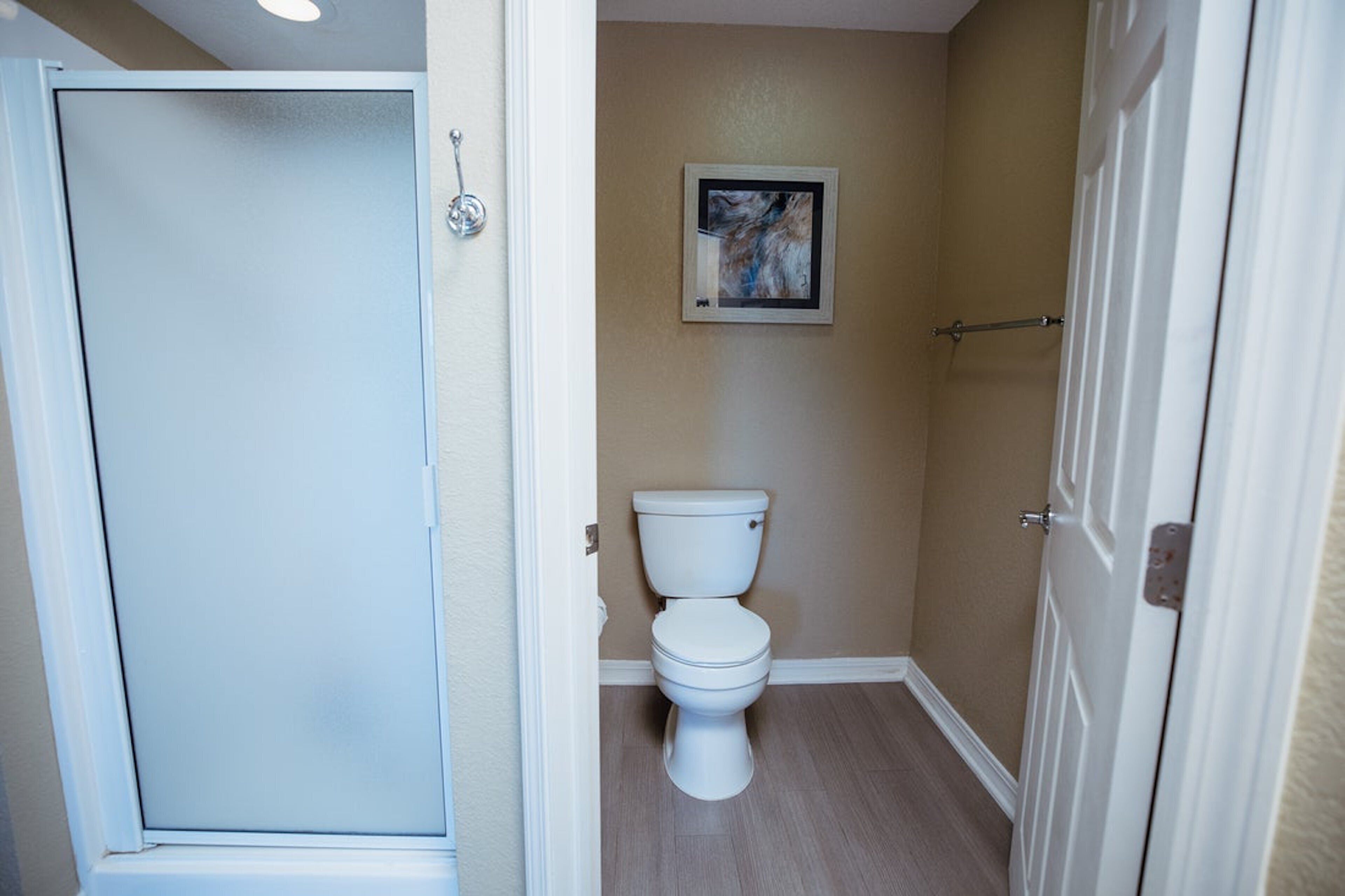 Ein Badezimmer mit Toilette, einer Duschkabine und einem gerahmten Bild an der Wand.