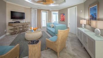 A modern living room with a television, sofa, wicker chairs, and a glass coffee table.