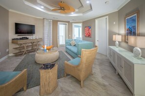 Un salon moderne comprenant un téléviseur, un canapé, des fauteuils en osier et une table basse en verre.